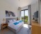 Bedroom 2 with a large double bed, wardrobe, workspace, TV, and access to the balcony