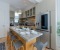 Open-plan kitchen equipped with a large fridge-freezer, gas stove, oven, microwave, toaster, and Nespresso machine