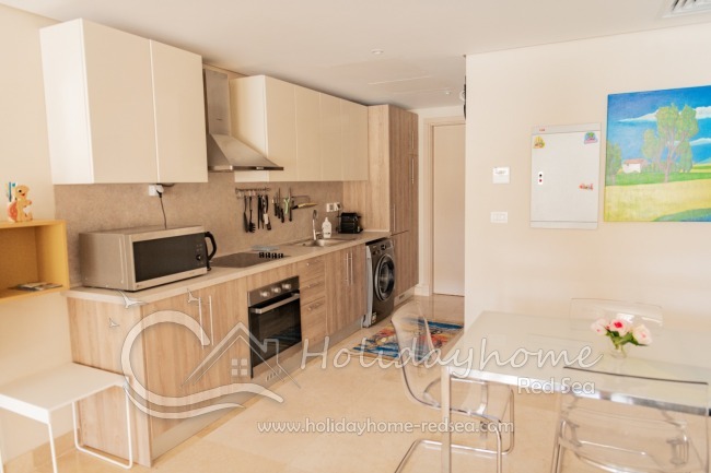 Full equipped kitchen with an adjoining living area , dining table, stove, oven, large fridge with freezer compartment, kettle, toaster, washing machine, microwave, nespresso machine