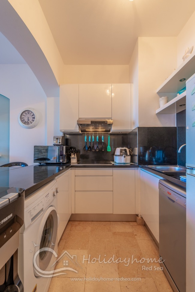 Fully equipped kitchen with washing machine, dishwasher, coffee maker, kettle, water dispenser, microwave, and toaster