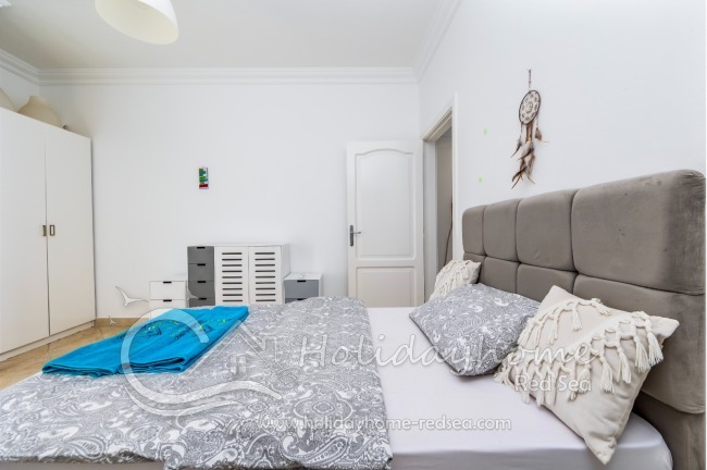 Cozy bed with pillows. Wardrobe and commode.