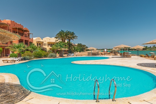 Shared pool with lagoon view, sunbeds and umbrella