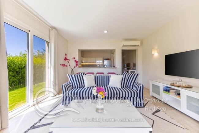 Living room with large TV, open kitchen and dining counter