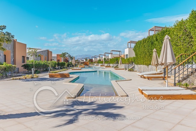 Shared pool with sunbeds and umbrellas