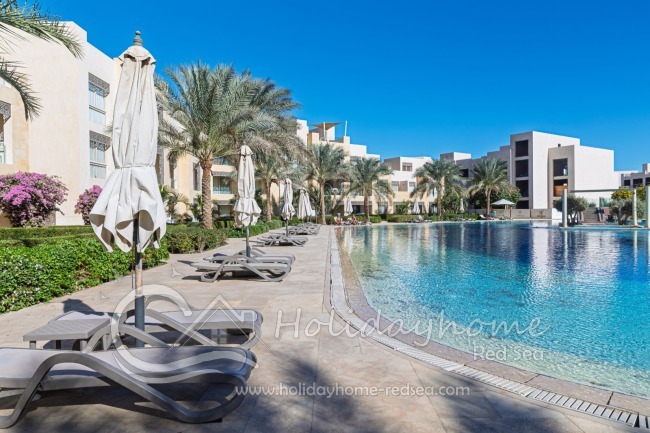 Shared pool with sunbeds and umbrellas