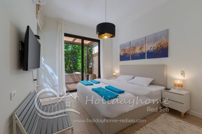 Bedroom 1 with a large double bed, wardrobe, and direct access to the terrace and garden