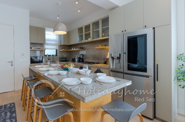 Open-plan kitchen equipped with a large fridge-freezer, gas stove, oven, microwave, toaster, and Nespresso machine