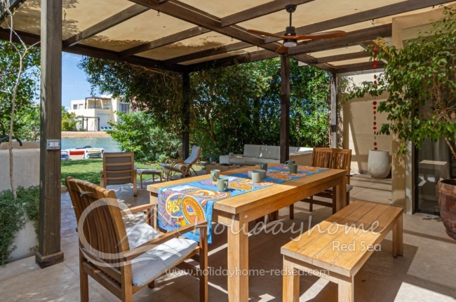Terrace with a large dining table, a cozy lounge area, and a garden