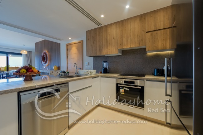 Fully equipped open-plan kitchen with all modern conveniences, including a blender, Dolce Gusto coffee machine, toaster, dishwasher, large refrigerator, and oven.